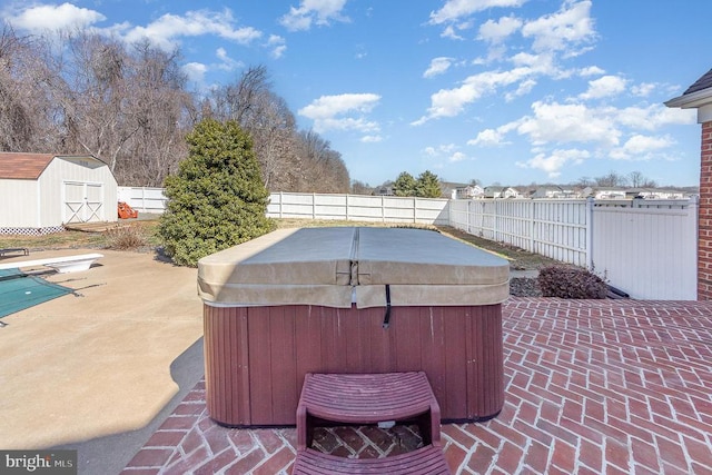 view of patio / terrace featuring a storage shed, a hot tub, a fenced backyard, and an outbuilding