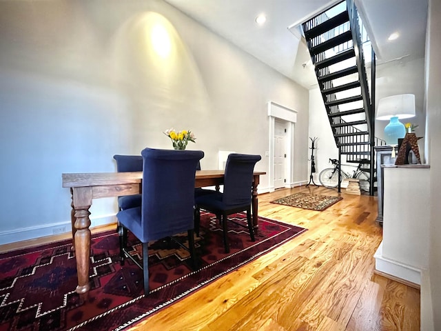 dining space with baseboards, stairs, a towering ceiling, and wood finished floors