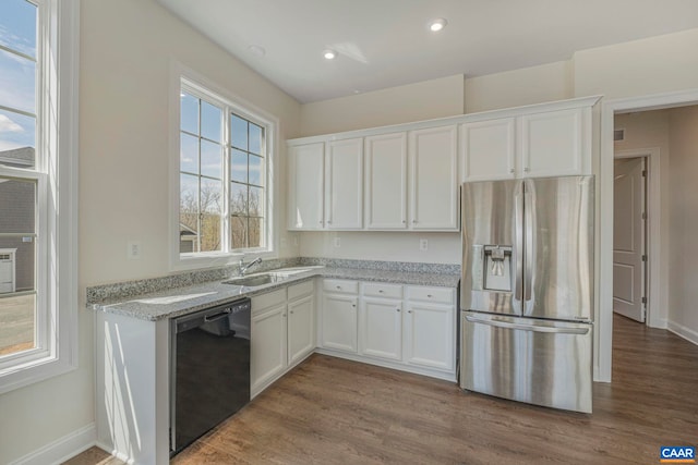 kitchen with stainless steel fridge, black dishwasher, white cabinetry, wood finished floors, and recessed lighting