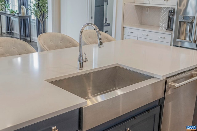 kitchen with backsplash, light countertops, a sink, and stainless steel dishwasher