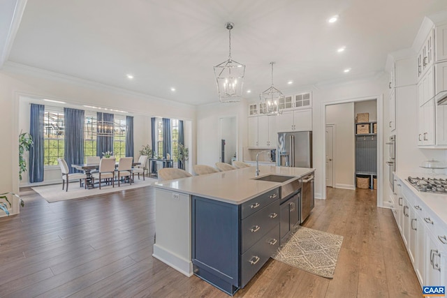 kitchen with stainless steel appliances, white cabinetry, light countertops, a sink, and recessed lighting