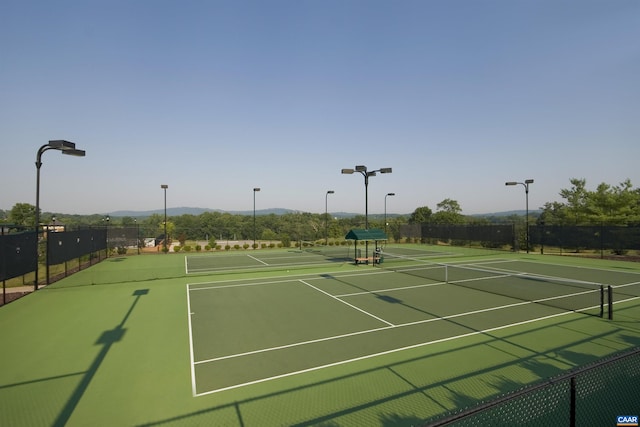 view of tennis court featuring fence, a mountain view, and community basketball court