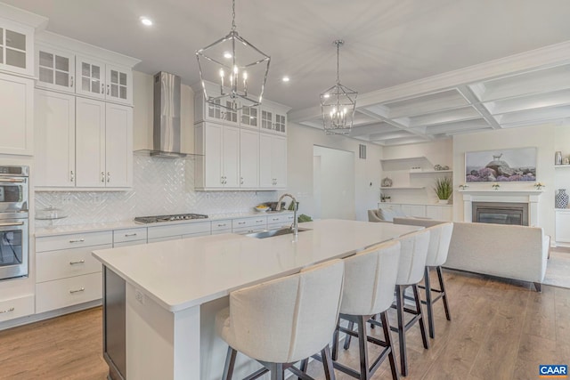 kitchen with wall chimney exhaust hood, a sink, gas stovetop, wood finished floors, and recessed lighting