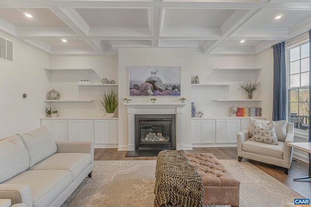 living area with wood finished floors, coffered ceiling, beamed ceiling, a fireplace with flush hearth, and recessed lighting