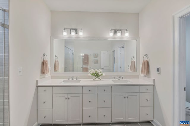 full bath with a stall shower, double vanity, and baseboards