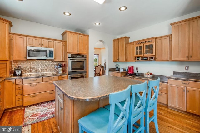 11425 Custers Trce, Spotsylvania, VA 22553 - kitchen featuring appliances with stainless steel finishes, light wood-style floors, a kitchen island, a kitchen breakfast bar, and dark countertops