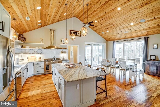 310 Elk Creek Lndg, Mineral, VA 23117 - kitchen featuring open shelves, stainless steel appliances, wall chimney exhaust hood, a breakfast bar, and light stone counters