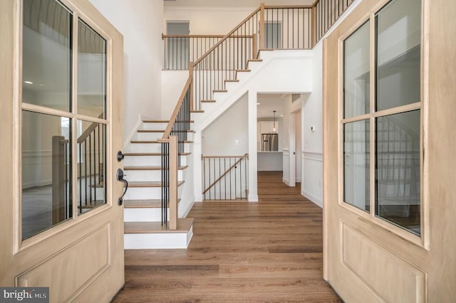  - stairs with wood finished floors, a high ceiling, and ornamental molding