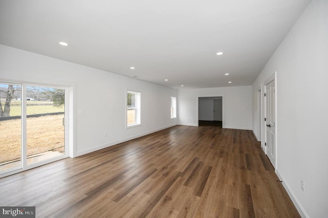 - unfurnished living room featuring plenty of natural light, recessed lighting, wood finished floors, and baseboards