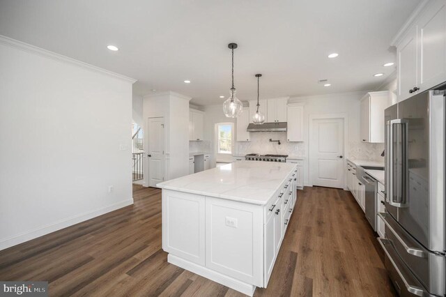  - kitchen featuring appliances with stainless steel finishes, under cabinet range hood, a center island, decorative backsplash, and white cabinetry