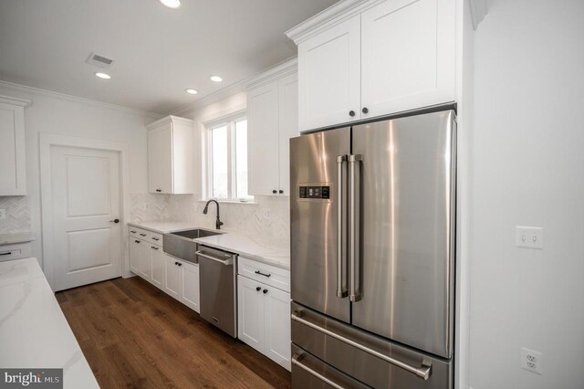  - kitchen featuring stainless steel appliances, a sink, white cabinets, dark wood finished floors, and backsplash