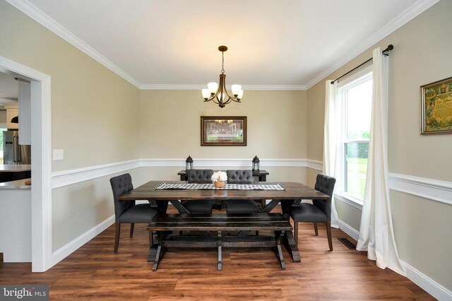  - dining room with a chandelier, wood finished floors, ornamental molding, and baseboards