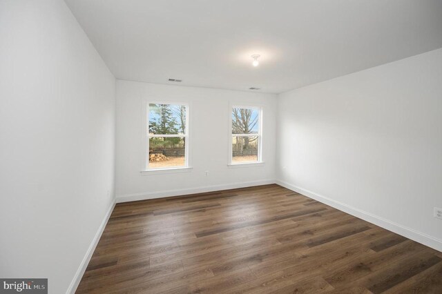  - empty room with dark wood-style flooring and baseboards