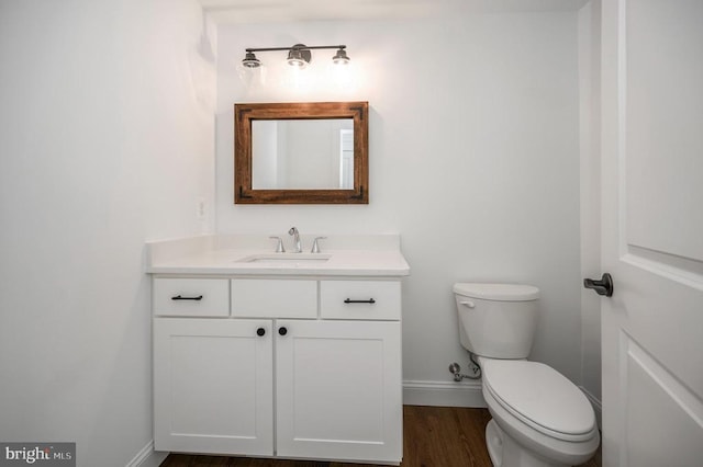  - half bathroom featuring baseboards, vanity, toilet, and wood finished floors