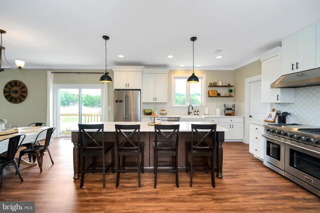  - kitchen with high quality appliances, under cabinet range hood, light countertops, a breakfast bar area, and ornamental molding