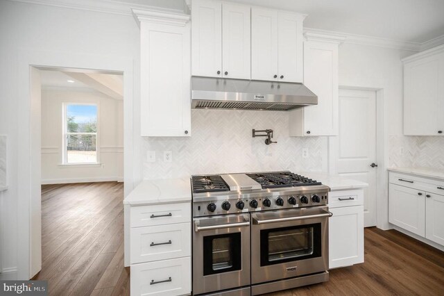 - kitchen featuring range with two ovens, under cabinet range hood, dark wood finished floors, crown molding, and light stone countertops