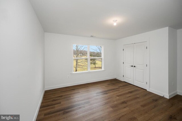  - unfurnished bedroom with dark wood finished floors, baseboards, and a closet