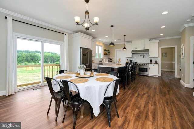  - dining room featuring crown molding, a chandelier, dark wood-style flooring, healthy amount of natural light, and baseboards