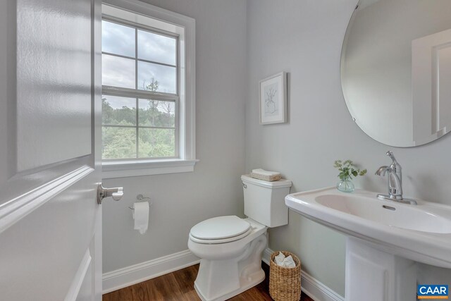 half bath with a sink, toilet, baseboards, and wood finished floors