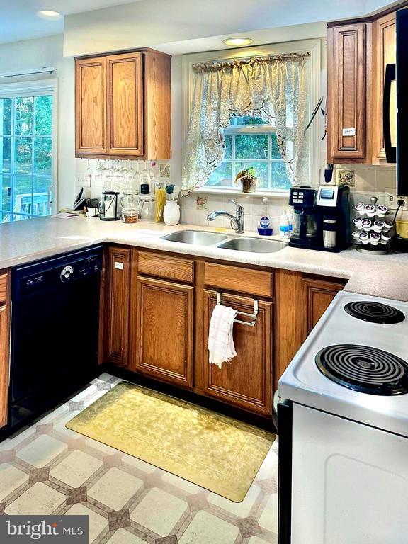 26 Magnolia Ct, Barboursville, VA 22923 - kitchen featuring white range with electric stovetop, dishwasher, a sink, brown cabinets, and light flooring