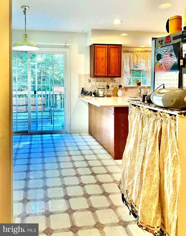 26 Magnolia Ct, Barboursville, VA 22923 - kitchen with a peninsula, backsplash, light countertops, decorative light fixtures, and brown cabinetry