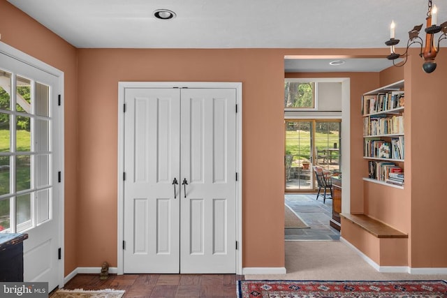 - doorway featuring baseboards and a chandelier