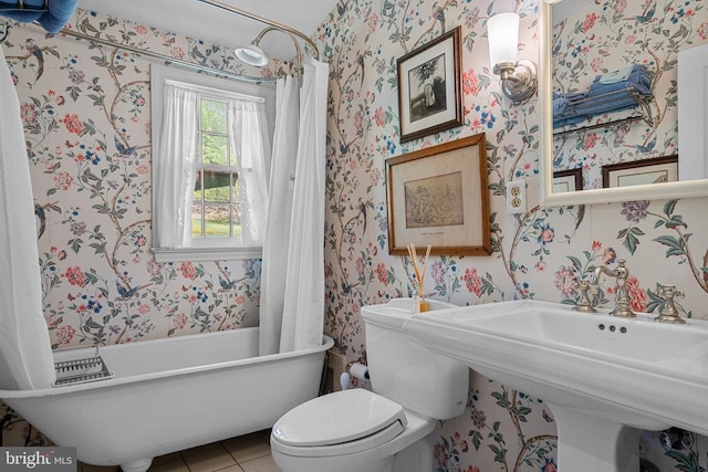  - full bath featuring wallpapered walls, a soaking tub, toilet, and tile patterned flooring