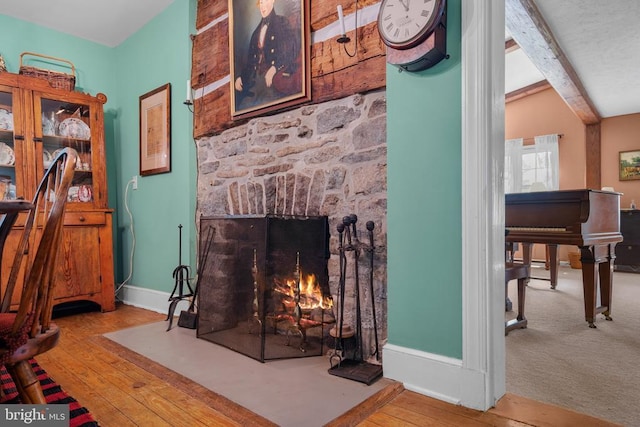  - living room featuring a large fireplace, wood-type flooring, baseboards, and beam ceiling