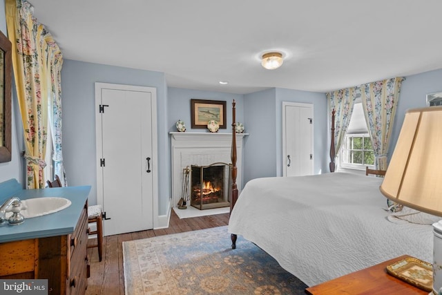  - bedroom with wood finished floors, a sink, and a fireplace