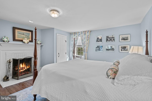  - bedroom with wood finished floors and a brick fireplace