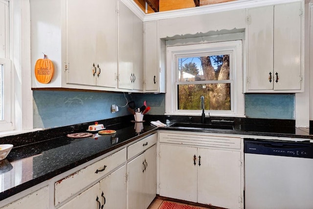 kitchen featuring white cabinetry, sink, stainless steel dishwasher, and dark stone counters