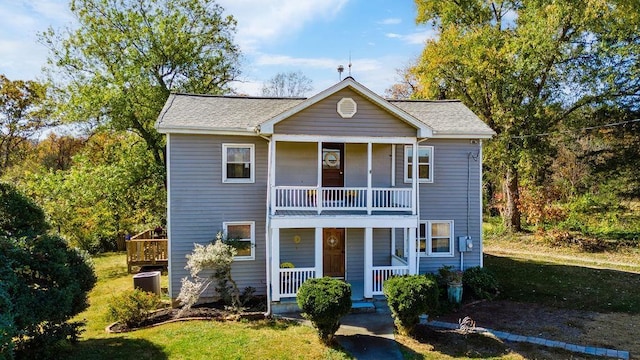 view of front of house with a porch, a balcony, central AC, and a front yard