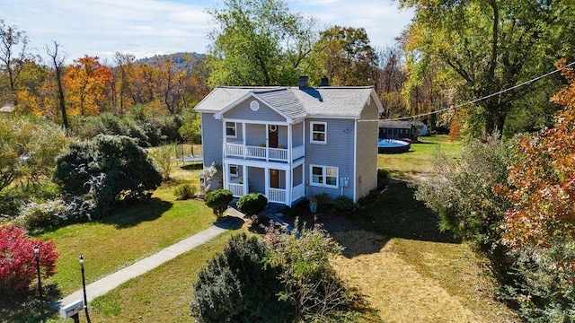 back of house with a balcony and a yard