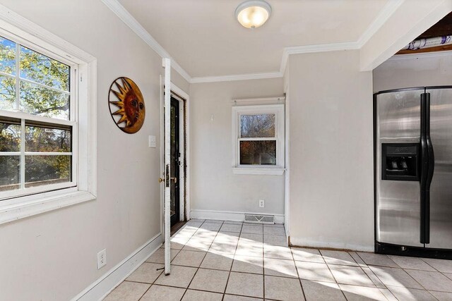 foyer entrance with crown molding and light tile patterned floors