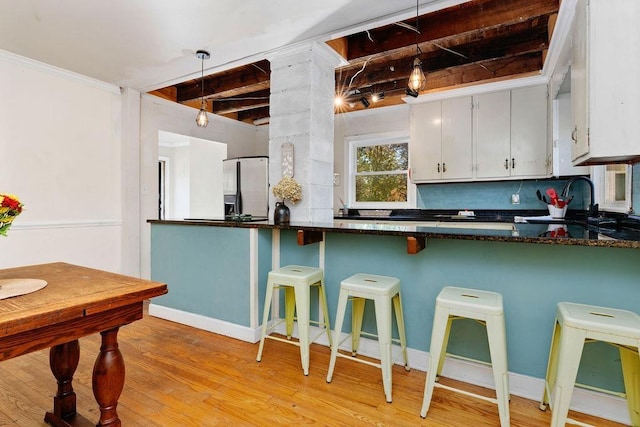 kitchen with kitchen peninsula, decorative backsplash, light wood-type flooring, and stainless steel fridge with ice dispenser