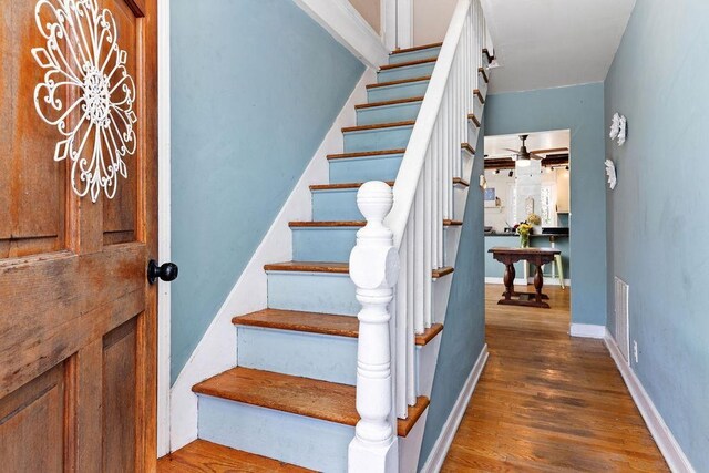 stairs featuring wood-type flooring and ceiling fan