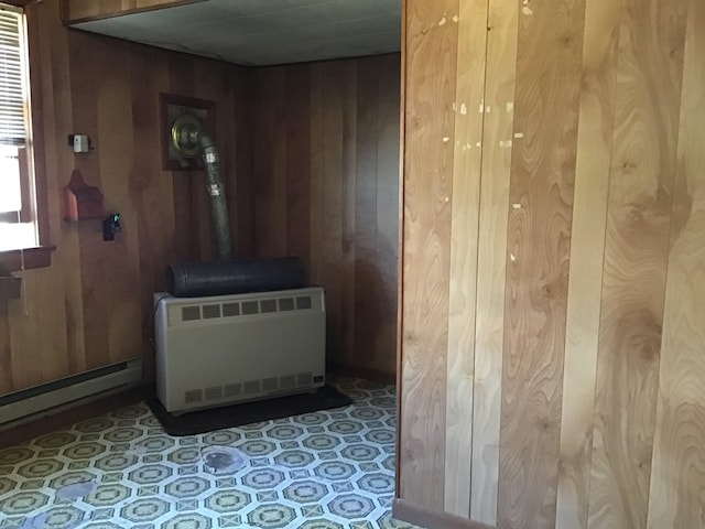 room details with wooden walls, heating unit, and a wood stove