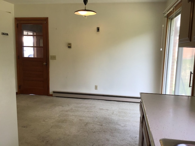 unfurnished dining area featuring a baseboard heating unit and carpet