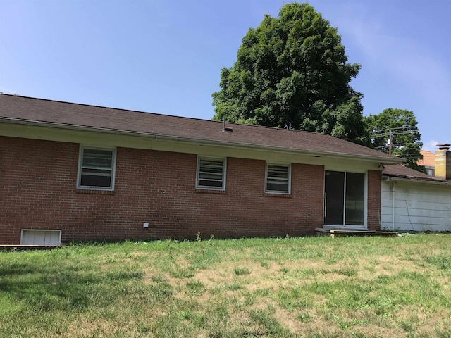 back of property featuring a yard and brick siding