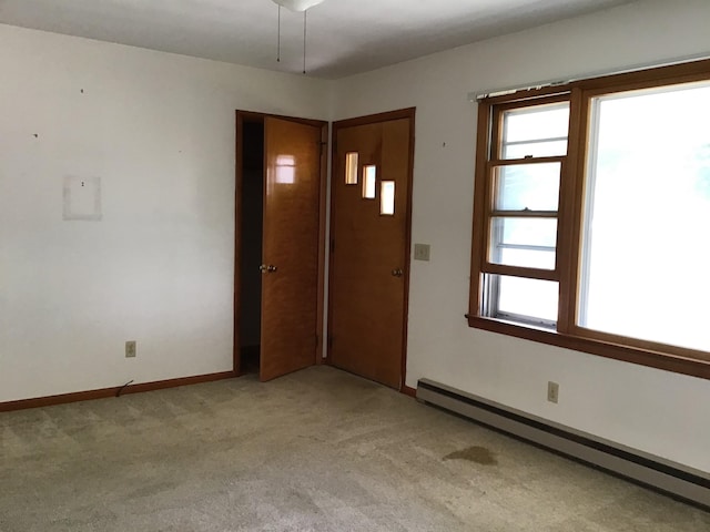 spare room with light colored carpet, baseboards, and baseboard heating