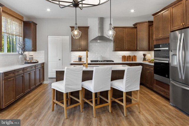 10100 N Streamview Ct, Fredericksburg, VA 22408 - kitchen with wall chimney range hood, stainless steel appliances, an island with sink, light countertops, and tasteful backsplash