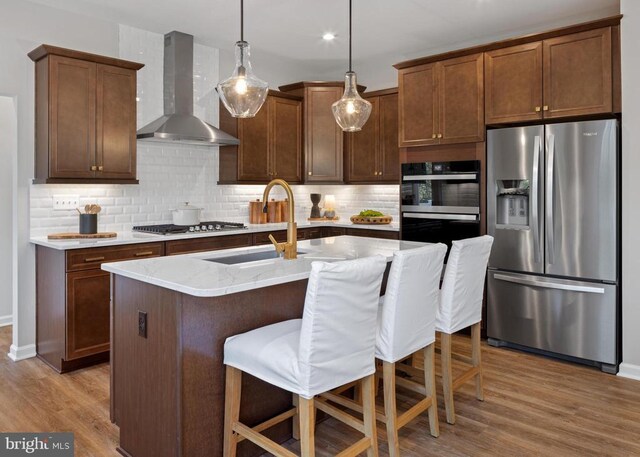 10100 N Streamview Ct, Fredericksburg, VA 22408 - kitchen with stainless steel appliances, wall chimney range hood, a sink, decorative backsplash, and wood finished floors