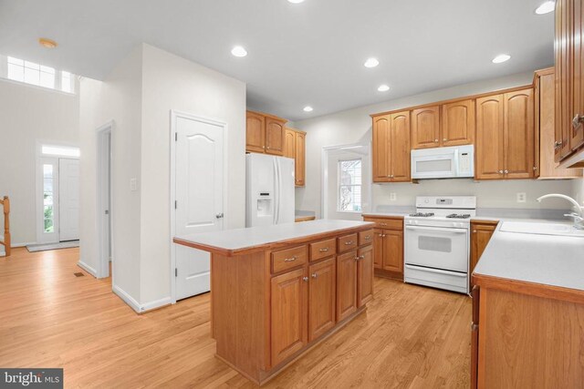 11218 Glen Park Dr, Fredericksburg, VA 22407 - kitchen featuring white appliances, a sink, a kitchen island, light wood finished floors, and light countertops