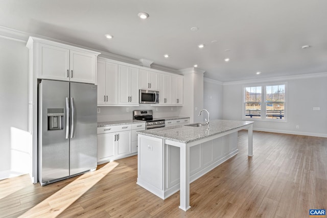 kitchen featuring a sink, white cabinets, crown molding, a kitchen island with sink, and appliances with stainless steel finishes