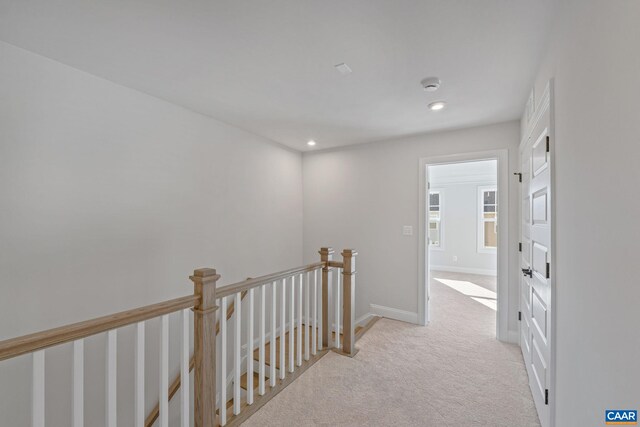 corridor featuring light colored carpet, baseboards, an upstairs landing, and recessed lighting