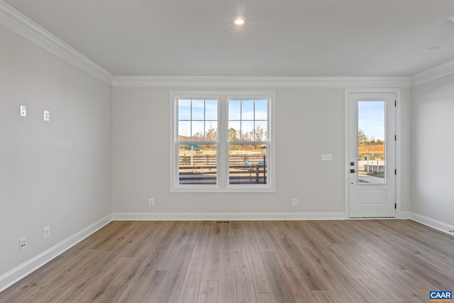 unfurnished room with crown molding, light wood-type flooring, visible vents, and baseboards
