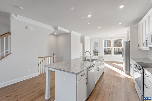kitchen with a sink, white cabinets, light wood-type flooring, a center island with sink, and appliances with stainless steel finishes