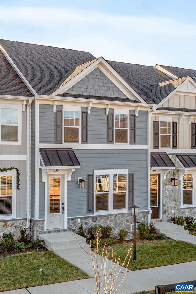 multi unit property with metal roof, roof with shingles, a standing seam roof, and stone siding