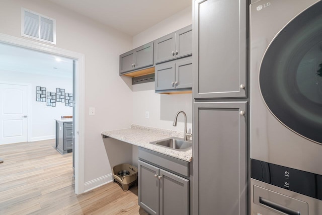 237 Ridgeline Dr, Waynesboro, VA 22980 - kitchen with estacked washer and dryer, a sink, gray cabinets, and light wood finished floors