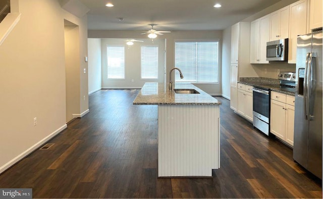12107 Bowling Farm Ct, Fredericksburg, VA 22407 - kitchen with stainless steel appliances, dark stone countertops, an island with sink, a ceiling fan, and white cabinetry